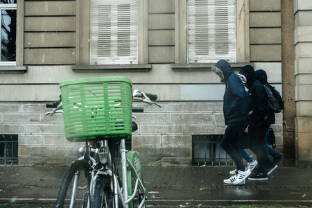 STRASBOURG, FRANCE - JAN 4, 2017: Snowstorm in France with young boys on a snowy day trying to hide from the cold weatherのeditorial素材