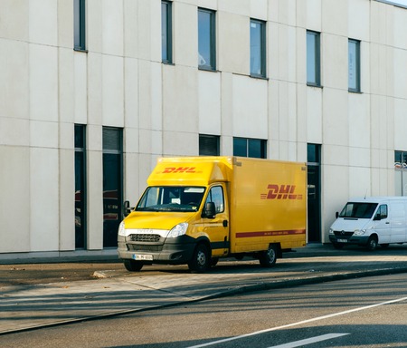 FRANKFURT, GERMANY - JAN 16, 2017: DHL Deutsche Post German postal yellow parcel distribution wvan parked on a German street near office industrial building mall storeのeditorial素材