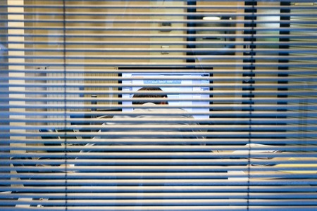 Silhouette of working late businessman man seen through windows blinds working at report thesis data analysis bank report view from the street - working lateの写真素材