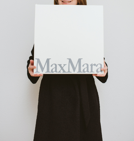 PARIS, FRANCE - FEB 16, 2018: Smiling elegant fashionista woman holding Max Mara Italian cardboard fashion  parcel box being happy with her purchase of the new coatのeditorial素材