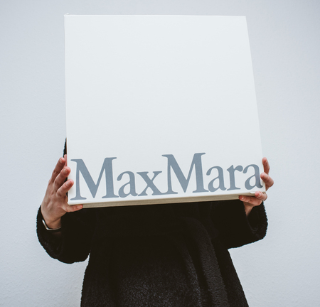 PARIS, FRANCE - FEB 16, 2018: Beautiful elegant fashionista woman holding Max Mara Italian cardboard fashion  parcel box being happy with her purchase of the new coatのeditorial素材
