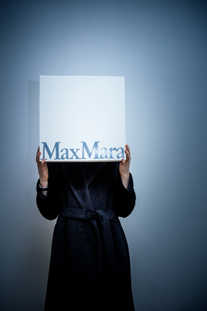 PARIS, FRANCE - FEB 16, 2018: Hiding face elegant fashionista woman holding Max Mara Italian cardboard fashion  parcel box being happy with her purchase of the new coat - blue backgroundのeditorial素材