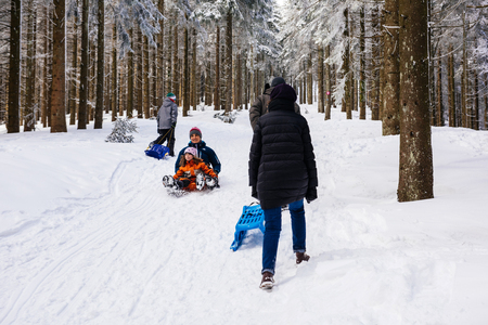MUMMELSEE, GERMANY - FEB 18, 2018: Winter day with snow and happy mother and doughter sleighing the sledding slope on a sunny winter day - great family timeのeditorial素材