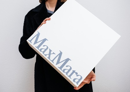 PARIS, FRANCE - FEB 16, 2018: Smiling elegant fashionista woman holding Max Mara Italian cardboard fashion  parcel box being happy with her purchase of the new coatのeditorial素材