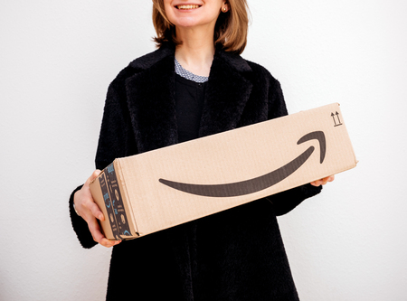 PARIS, FRANCE - FEB 16, 2018: Smiling elegant fashionista woman holding Amazon Prime cardboard parcel box against white backgroundのeditorial素材