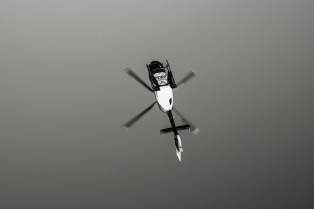 BADEN WURTTEMBERG, GERMANY - FEB 25, 2018: View from below of rescue helicopter DRF Luftrettung Notartzt flying in clear blue sky transporting a victim to hospital black and whiteのeditorial素材