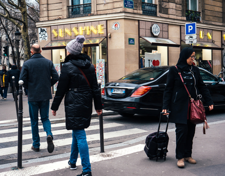 PARIS, FRANCE - JAN 30, 2018: French male and female crossing street in front of Mercedes -Benz luxury limousine in Paris, on the Rue St Vincent de Paulのeditorial素材