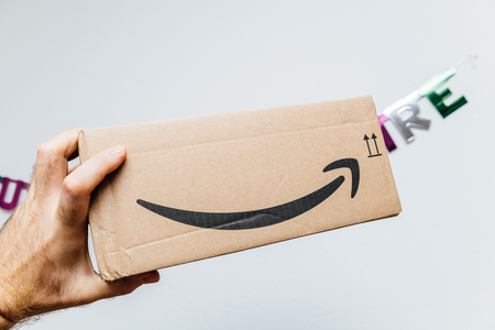PARIS, FRANCE - JAN 6, 2018: Amazon cardboard parcel box with smile arrow logotype against Joyeux Anniversaire text happy Birthday partyのeditorial素材