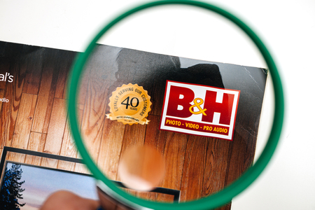 PARIS, FRANCE - 14 JAN 2018: B H photo Video pro Audio Magazine catalogue electronics and technology pov using magnifying glass loupeのeditorial素材