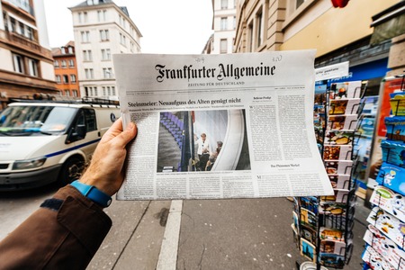 PARIS, FRANCE - MAR 15, 2017: Man reading buying German Frankfurter Allgemeine Zeitung newspaper at press kiosk featuring Angela Dorothea Merkel re election as Chancellor of Germanyのeditorial素材