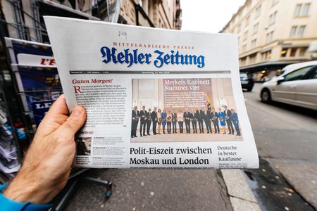 PARIS, FRANCE - MAR 15, 2017: Man reading buying German Kehler Zeitung newspaper at press kiosk featuring Angela Dorothea Merkel re election as Chancellor of Germany teamのeditorial素材