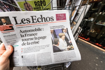 PARIS, FRANCE - MAR 15, 2017: Man reading buying French Les Echos newspaper at press kiosk featuring Angela Dorothea Merkel re election as Chancellor of Germanyのeditorial素材