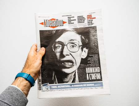 PARIS, FRANCE - MAR 19, 2018: Man reading French Liberation newspaper with portrait of Stephen Hawking the English theoretical physicist, cosmologist dead on 14 March 2018のeditorial素材