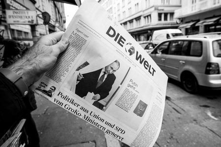 PARIS, FRANCE - MAR 19, 2017: Man reading buying German Die Welt newspaper at press kiosk featuring Russian presidential election from 2018 with the winner Vladimir Putin city backgroundのeditorial素材