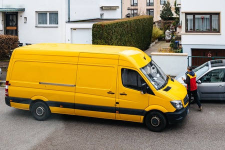 PARIS, FRANCE - MAR 30, 2018: Courier enters DHL yellow delivery van after delivering the on time delivering package parcel in typical European neighborhood - elevated viewのeditorial素材