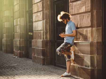 STRASBOURG, FRANCE - 13 MAR, 2018: Young man with long hair using the free wi-fi on his smartphone next to the Apple Store entrance in Strasbourgのeditorial素材