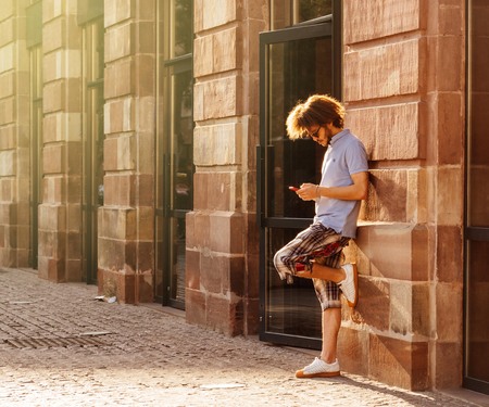 STRASBOURG, FRANCE - 13 MAR, 2018: Handsome man with long hair using the free wi-fi on his smartphone next to the Apple Store entrance in Strasbourg