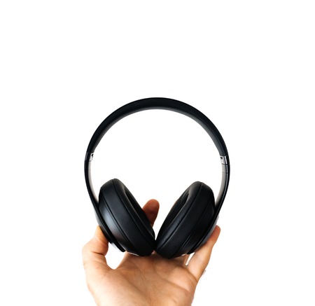 Man holding black headphones wireless headphones on white backgroundの写真素材