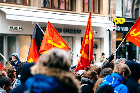 STRASBOURG, FRANCE  - MAR 22, 2018: Young communist flags in hands at demonstration protest against Macron French government string of reforms, mutiple trade unions called public workers to strikeのeditorial素材