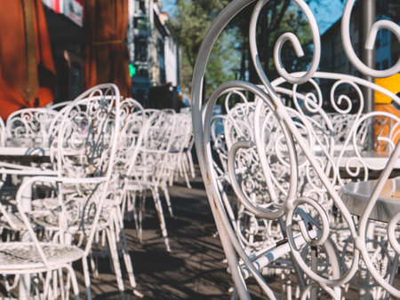 Classic forged white metal chairs with pattern in traditional style of an Italian Ice Cream gelateria on the sunny street in German streetの写真素材
