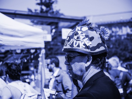 STRASBOURG, FRANCE - MAY 5, 2018: People making a party protest Fete a Macron party for Macron - man with military helmet with NO NUKE text and flowers - blue castのeditorial素材
