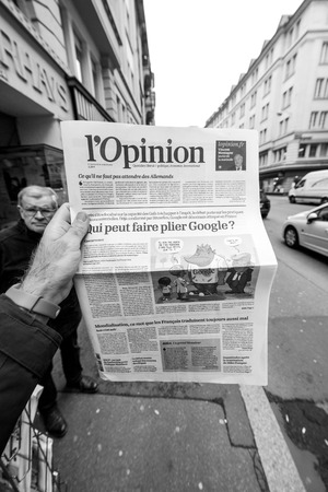 PARIS, FRANCE - MAR 15, 2018: POV man holding Opinion French newspaper with article about Google on front pageのeditorial素材