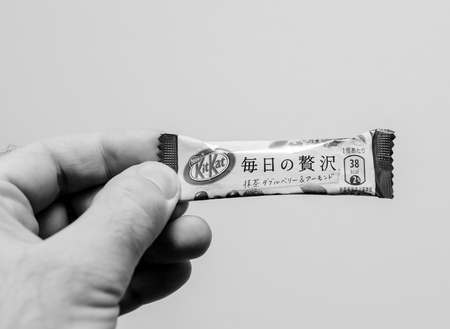 BERLIN, GERMANY - MAR 3, 2018: Man holding against white background Japanese Kit Kat cookie chocolate Nestle - black and whiteのeditorial素材