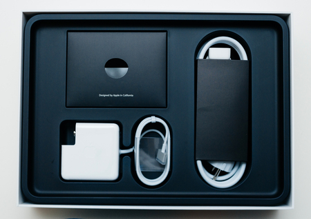 LONDON, UNITED KINGDOM - JAN 14, 2015: View from above New Apple MacBook Pro laptop computer with fast processors and GPU unboxing with Designed by Apple in California signage on accessoriesのeditorial素材