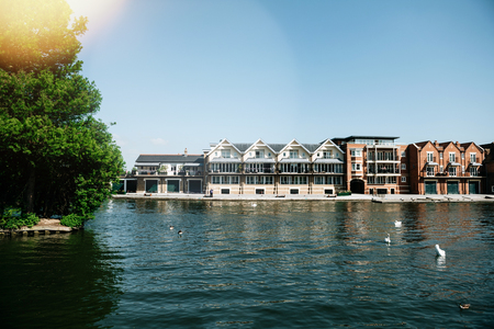 WINDSOR, BERKSHIRE, UNITED KINGDOM - MAY 19, 2018: Luxury houses on Tamisa river with swans and blue clear skyのeditorial素材