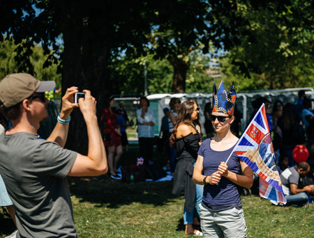 WINDSOR, BERKSHIRE, UNITED KINGDOM - MAY 19, 2018: Man taking photo of woman with flag at royal wedding marriage celebration of Prince Harry, Duke of Sussex and the Duchess of Sussex Meghan Markleのeditorial素材