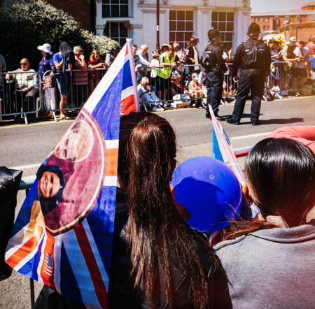 WINDSOR, BERKSHIRE, UNITED KINGDOM - MAY 19, 2018: Woman with couple flag near waits for fence for royal wedding marriage celebration of Prince Harry and Meghan Markleのeditorial素材