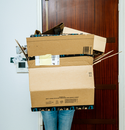 PARIS, FRANCE - JAN 13, 2018: Square image of woman holding stack of Amazon Prime packages delivered to a home door woman hiding behind heavy boxesのeditorial素材