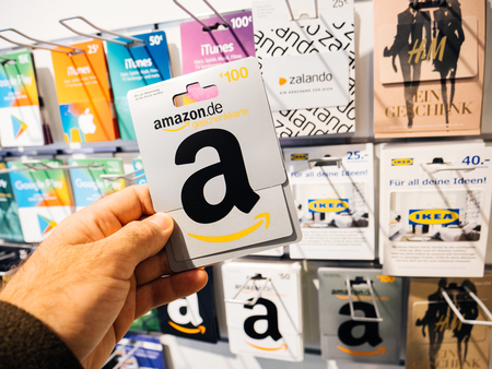 FRANKFURT, GERMANY - OCT 6, 2017: 50 Euro card in man hand point of view customer shopping for prepaid Amazon Gift card online money prepaid cards on shelf for online applications computer online store geschenckkarteのeditorial素材