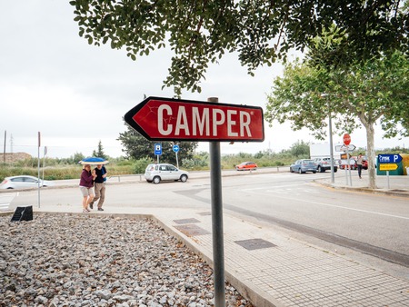 INCA, PALMA DE MALLORCA, SPAIN - MAY 8, 2018: Couple walking to Camper shoe factory headquarter in Inca with logotype on totem arrow traffic sign. Camer is a footwear company with headquarters in Mallorca, Spainのeditorial素材