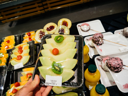 FRANKFURT, GERMANY - NOV 25, 2017: Male customer point of view buying vegan and vegetarian food in German supermarket Edeka - choosing the fresh melon cut fruits with kiwiのeditorial素材