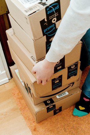 PARIS, FRANCE - JAN 13, 2018: Overhead shot of stack Amazon Prime packages delivered to a home door woman trying to lift heavy boxesのeditorial素材