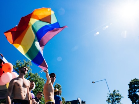 STRASBOURG, FRANCE - JUN 10, 2017: Defocused group of caucasian excited gay men waving rainbow flag against blue sky LGBT visibility march pride in Strasbourgのeditorial素材
