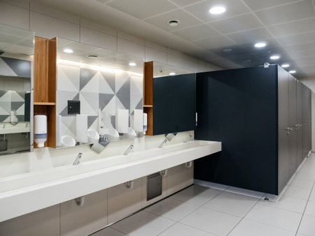 Interior of male bathroom toilet inside modern airport - sink and toilet cabines