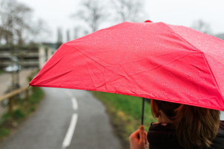 Rear view of woman with red umbrella walking in city on a warm spring day - book cover and cinematic