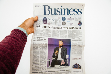 PARIS, FRANCE - JUN 13, 2018: Man holding The Daily Telegraph with portrait of Elon Musk CEO of tesla saying he is cutting 9 percent of jobsのeditorial素材