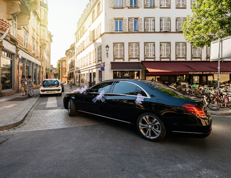 STRASBOURG, FRANCE - JUN 30, 2018: Luxury Black Mercedes Benz AMG S320 4matic driving on French street - car is decorated for wedding with silk details on door handles - sunlight flareのeditorial素材