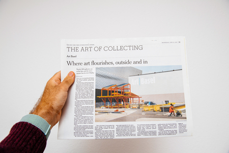 PARIS, FRANCE - JUNE 13, 2018: Man holding newspaper The New York Times newspaper about Art Basel Modern art exhibition in Basel, Switzerlandのeditorial素材