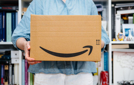 PARIS, FRANCE - JUL 4, 2018: Woman receiving Amazon Prime package delivered preparing to do the...