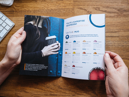 PARIS, FRANCE - JUL 1, 2018: Woman reading advertising leaflet catalogue from Nespresso espresso machines brew espresso coffee coffee capsules with machines for home or professional useのeditorial素材