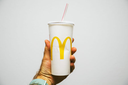 PARIS, FRANCE - JUL 27, 2018: Man holding against white background a cup of McDonalds Cola with...