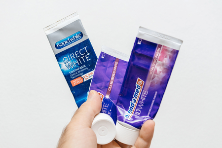 PARIS, FRANCE - JUL 28, 2018: Man holding in hand against white background medical toothpaste from Blend-a-med and Rapid White best toothpasteのeditorial素材
