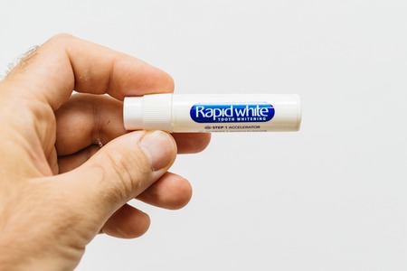 PARIS, FRANCE - JUL 28, 2018: Man holding in hand against white background medical toothpaste from Rapid White for teeth whiteningのeditorial素材