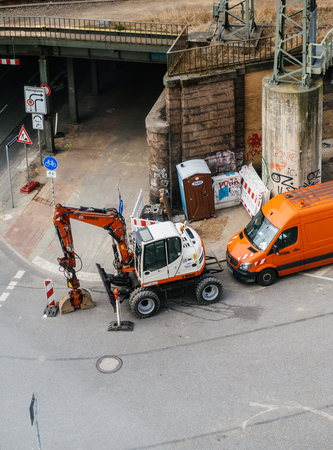 HAMBURG, GERMANY - MAR 21, 2018: From above shot of roadwork equipment excavator and orange service van on paved street near grungy bridge passageのeditorial素材