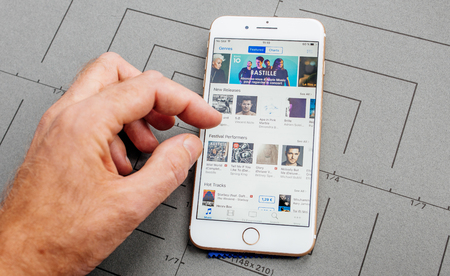 PARIS, FRANCE - SEP 26, 2016: Male hand holding New Apple iPhone  8 Plus smartphone after unboxing and testing by installing the app application software Featured charts Apple Musicのeditorial素材