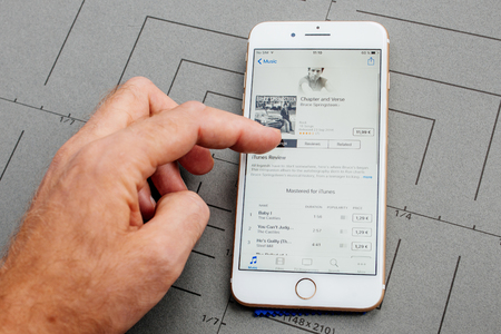 PARIS, FRANCE - SEP 26, 2016: Male hand holding New Apple iPhone  8 Plus smartphone after unboxing and testing by installing the app application software Apple Music Bruce Springsteen album buyのeditorial素材
